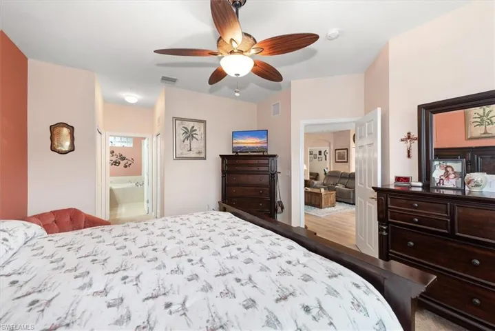 Bedroom featuring a ceiling fan, ensuite bath, and light wood-style floors