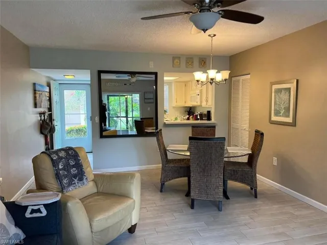 Dining room featuring a ceiling fan, wood finish floors, a textured ceiling, and a chandelier