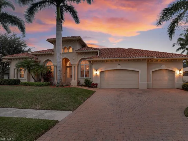 Mediterranean / spanish-style home with a lawn and a garage