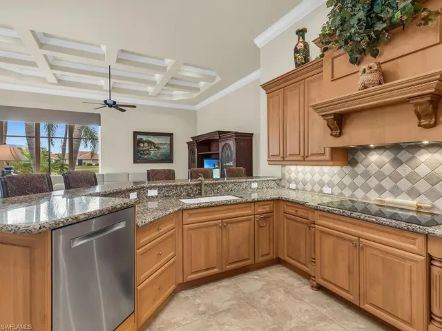 Kitchen featuring kitchen peninsula, crown molding, stainless steel dishwasher, black electric cooktop, and coffered ceiling