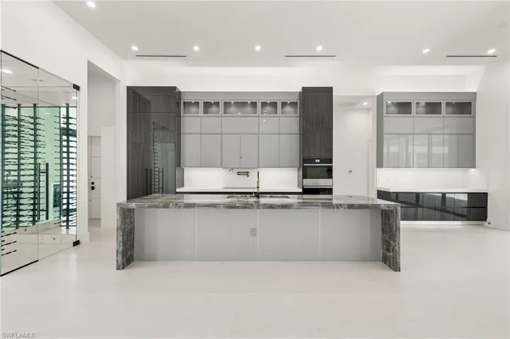Kitchen with stainless steel oven, sink, dark stone counters, and plenty of natural light