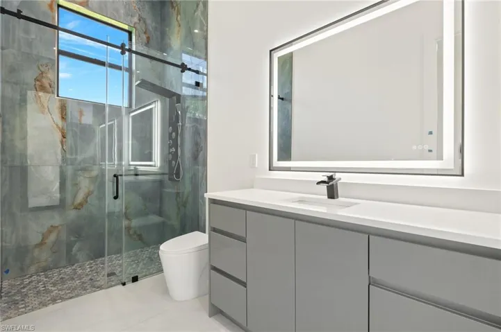 Bathroom with tile floors, walk in shower, toilet, and vanity