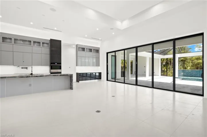 Unfurnished living room with a high ceiling, sink, and light tile floors