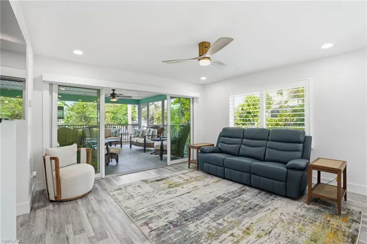 Living area featuring a ceiling fan, wood finished floors, a sunroom, and recessed lighting - Virtually Edited Image