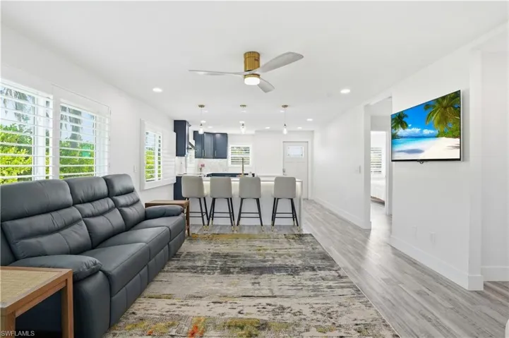 Living area with light wood-type flooring, ceiling fan, and recessed lighting - Virtually Edited Image