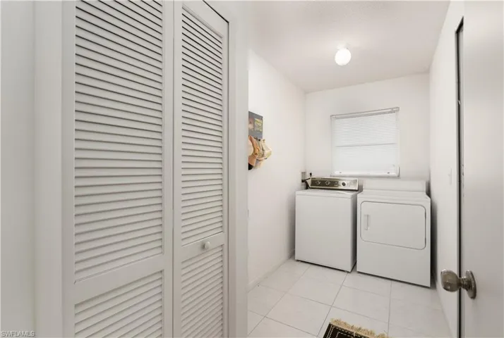 Laundry area with light tile patterned floors and washing machine and dryer
