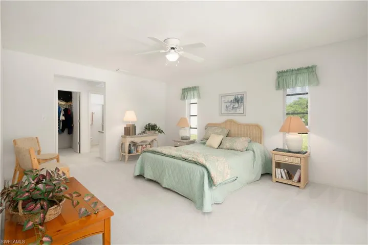 Carpeted bedroom with ceiling fan, a walk in closet, and a closet