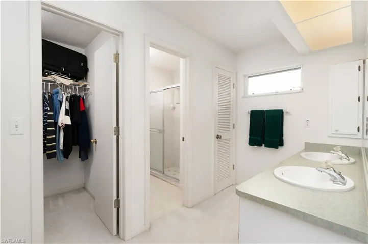 Bathroom with dual vanity, tile patterned floors, and an enclosed shower