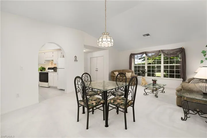 Carpeted dining space featuring vaulted ceiling
