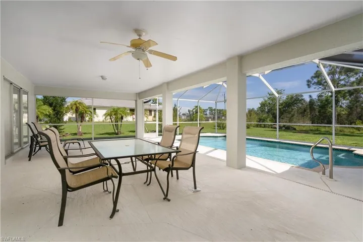 View of pool with ceiling fan, a patio area, a lanai, and a lawn