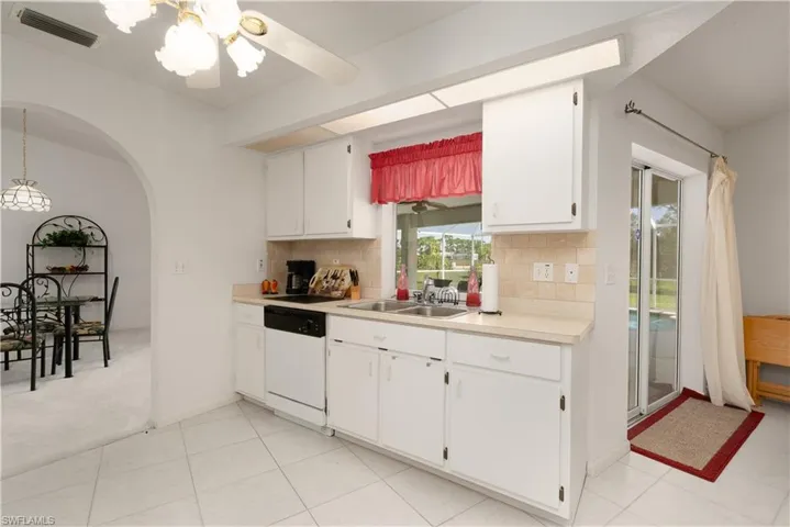 Kitchen featuring light tile patterned floors, sink, dishwasher, and backsplash