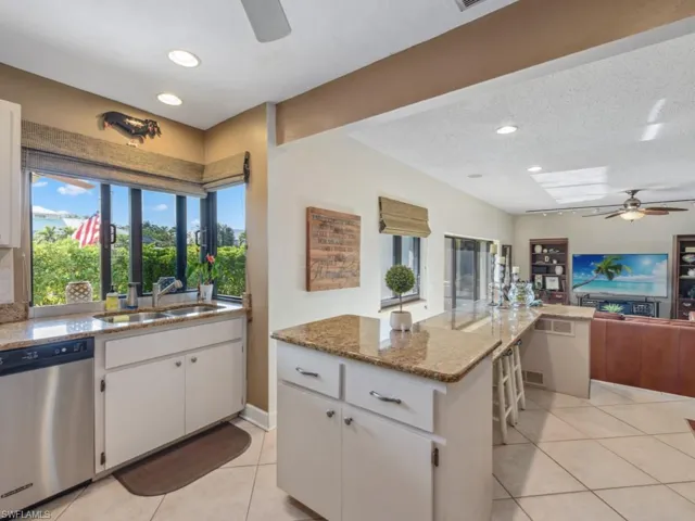 Kitchen featuring dishwasher, sink, light stone counters, a textured ceiling, and white cabinets