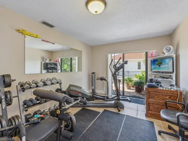 Exercise area featuring light tile patterned floors and a textured ceiling