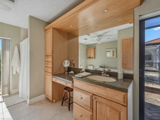 Bathroom with tile patterned floors, ceiling fan, vanity, and a textured ceiling