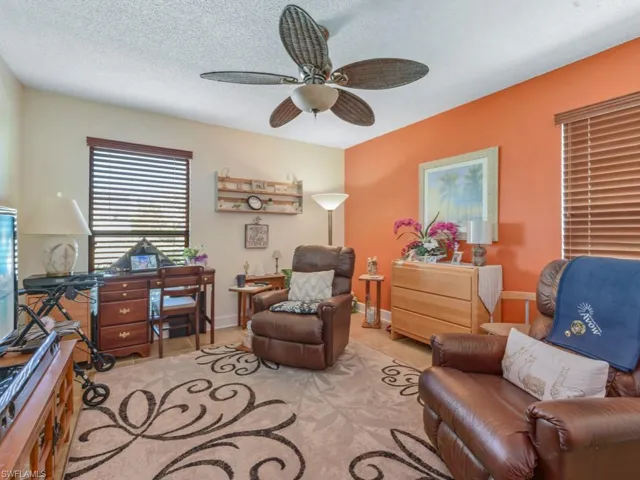 Living area with ceiling fan, light tile patterned floors, and a textured ceiling