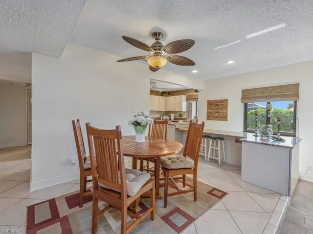 Dining space with light tile patterned floors, a textured ceiling, and ceiling fan