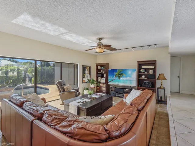 Tiled living room featuring ceiling fan and a textured ceiling