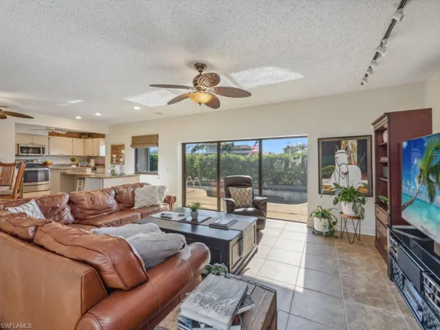 Tiled living room featuring a textured ceiling, track lighting, and ceiling fan