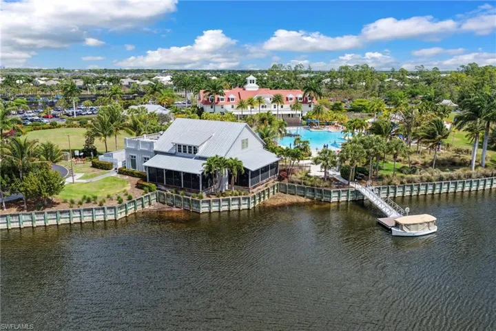 Waterfront building with screened porch and private dock, featuring a metal roof and a light-colored exterior