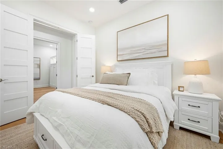 Bedroom featuring hardwood-style flooring, recessed lighting, and a white paneled door