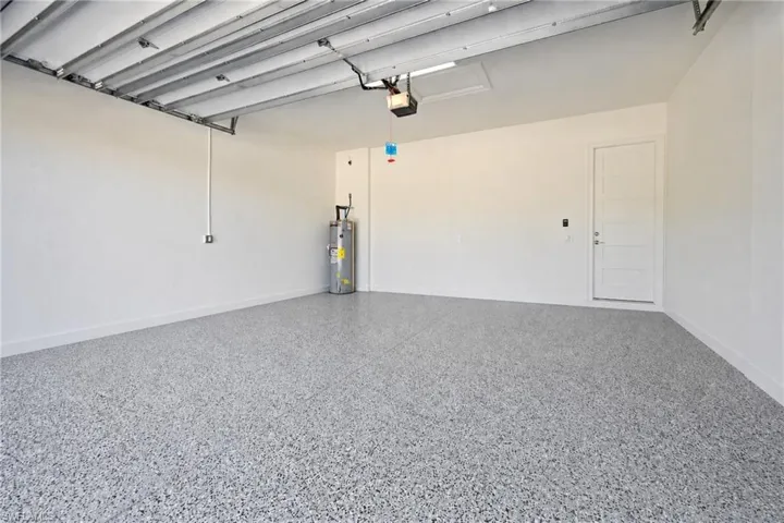 Spacious garage featuring a durable epoxy-coated floor, painted white walls, interior access door, and an overhead garage door opener