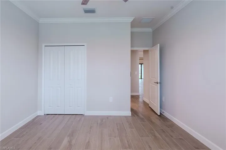Empty room with ornamental molding, light wood-type flooring, and a ceiling fan