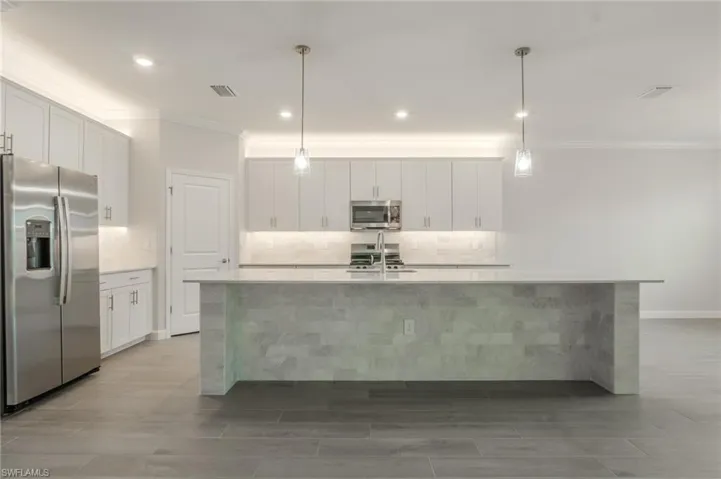 Kitchen with a raised ceiling, washer / clothes dryer, ornamental molding, light stone countertops, and open floor plan