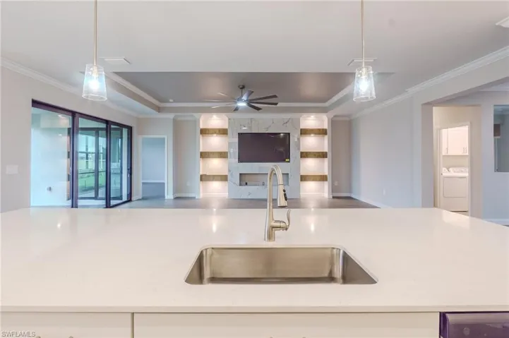 Kitchen with stainless steel appliances, crown molding, hanging light fixtures, a spacious island, and white cabinetry