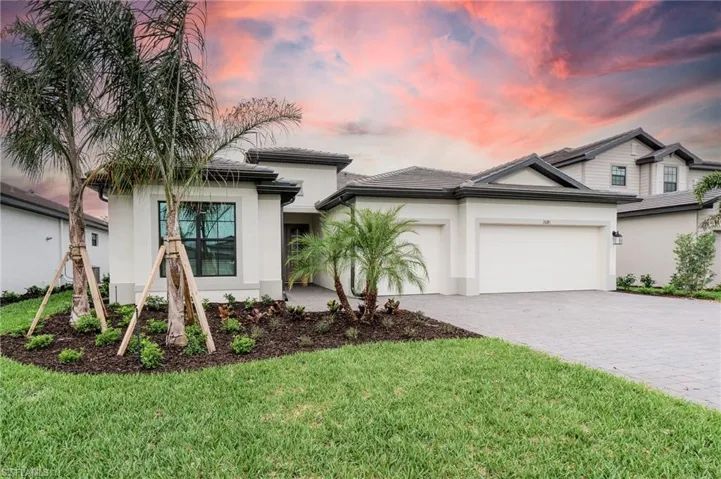 View of front of property featuring decorative driveway, an attached garage, stucco siding, and a lawn