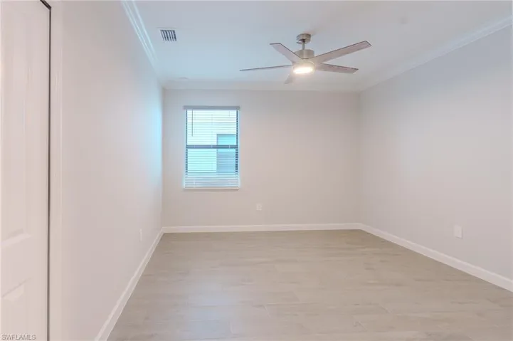 Bedroom featuring light wood-style floors, ornamental molding, and ceiling fan
