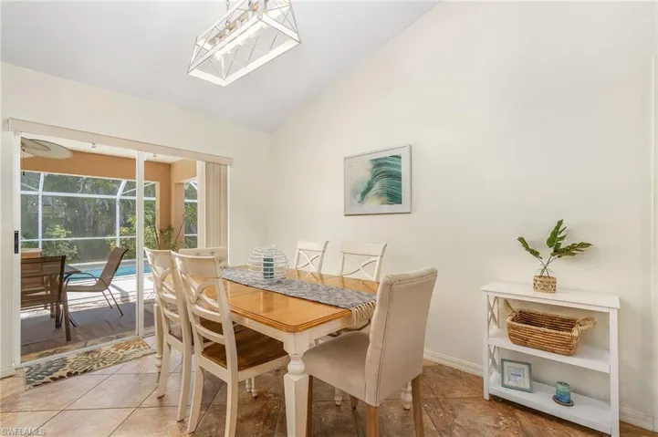 Dining area with lofted ceiling, a sunroom, and light tile patterned floors