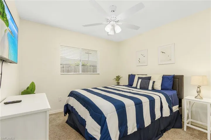 Bedroom with light colored carpet and a ceiling fan