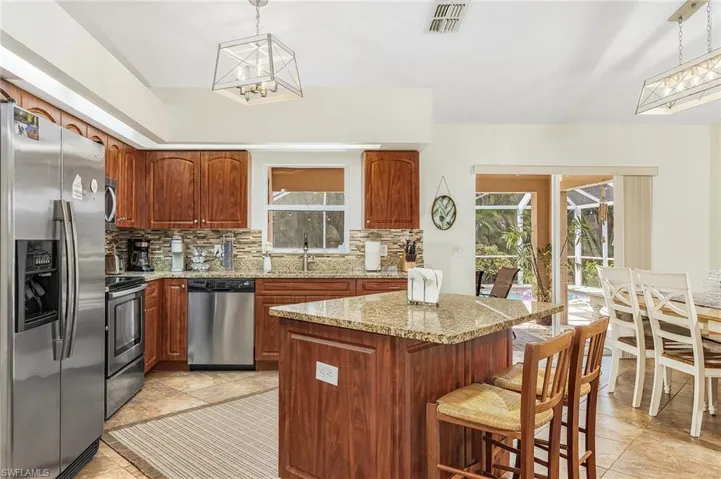 Kitchen featuring stainless steel appliances, tasteful backsplash, light stone counters, and a center island