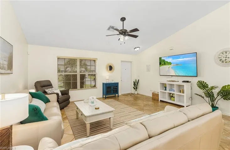 Living room with lofted ceiling, ceiling fan, and light tile patterned floors