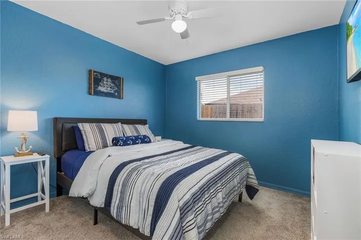 Bedroom featuring a textured wall, carpet flooring, and ceiling fan