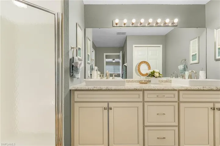 Bathroom featuring double vanity and a shower stall
