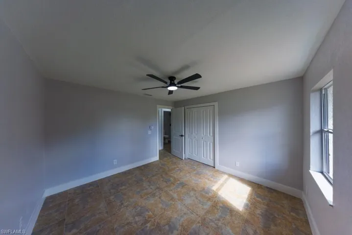 Cozy third bedroom filled with natural light, featuring a ceiling fan and neutral finishes, perfect for family or guests.