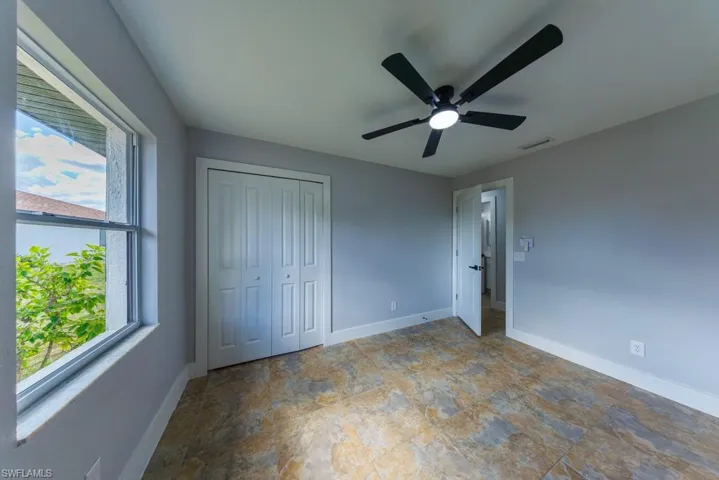 Spacious second bedroom featuring tile floors, a ceiling fan, and large windows that fill the space with natural light, ideal for guests or a home office.