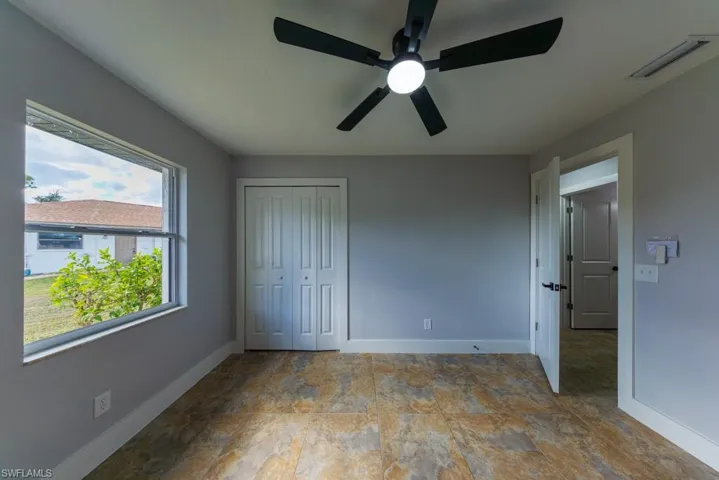 Bright and versatile second bedroom with tile flooring, ceiling fan, and generous natural light, perfect as a guest room, office, or creative retreat.