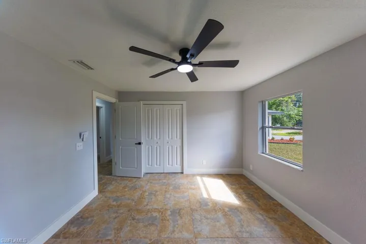 Inviting third bedroom with neutral finishes, ceiling fan, and plenty of natural light, a comfortable space for family or guests.