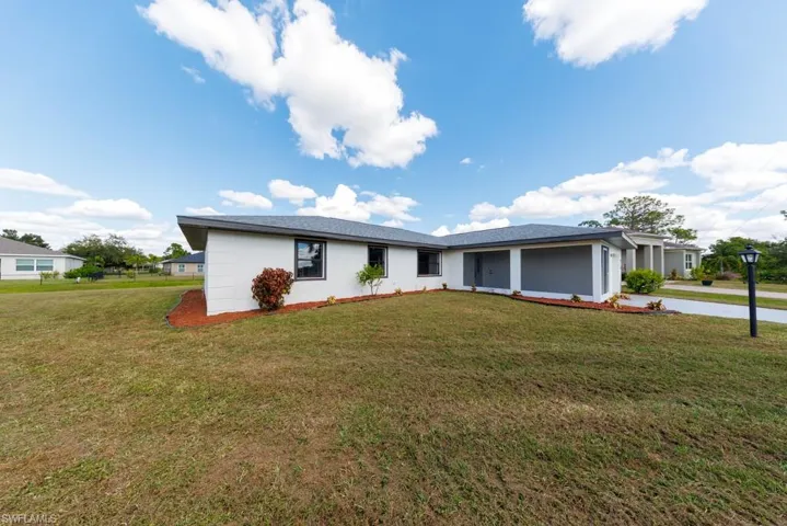 Side of single-story residence featuring a landscaped front yard, driveway, and stucco siding.