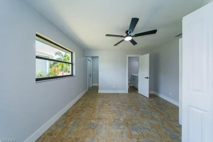 Spacious primary bedroom featuring tile flooring, ceiling fan, and abundant natural light, complete with a private ensuite bath for comfort and convenience