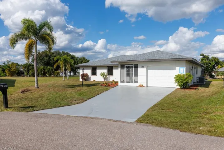 Spacious ranch-style residence featuring a landscaped front lawn, driveway, garage, and shingled roof.