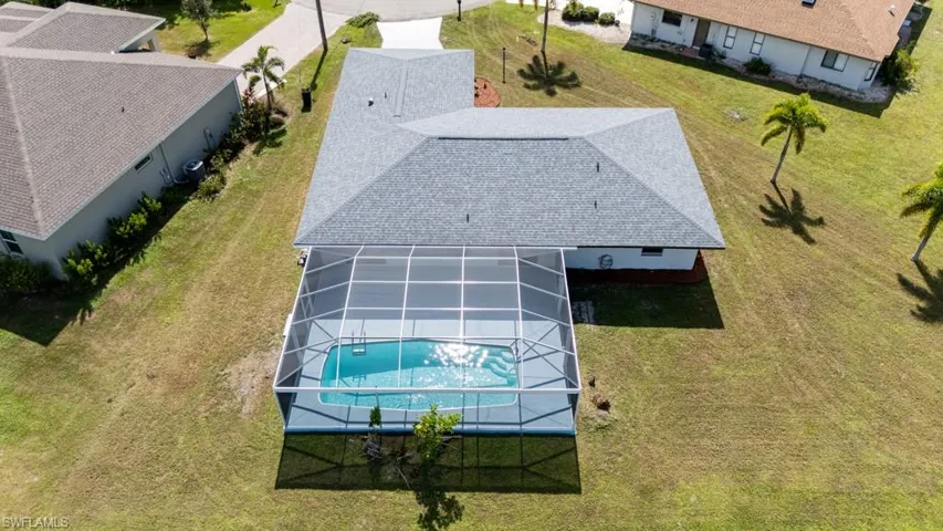 Aerial view of the property showcasing the screened-in pool and spacious backyard.