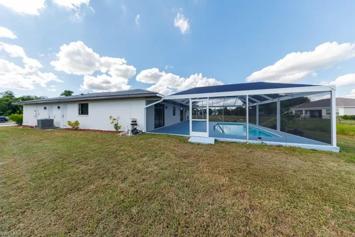 Rear exterior showcasing the new pool enclosure, outdoor pool, and green lawn
