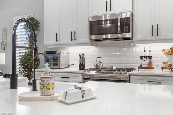 Kitchen featuring appliances with stainless steel finishes, backsplash, and white cabinets