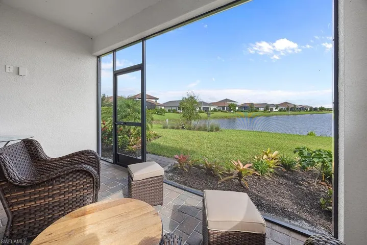 Sunroom with a textured wall, stone tile floors, a residential view, and a water view