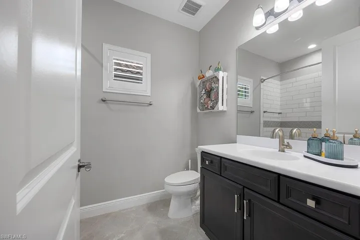 Full bathroom featuring vanity, tiled shower, and light tile patterned flooring
