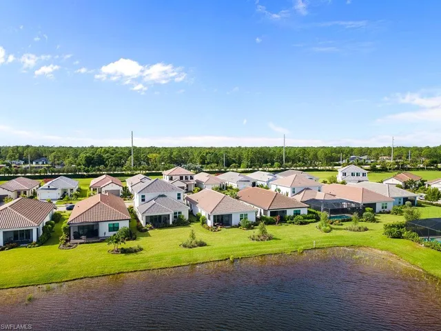Aerial perspective of suburban area with a nearby body of water and a tree filled landscape