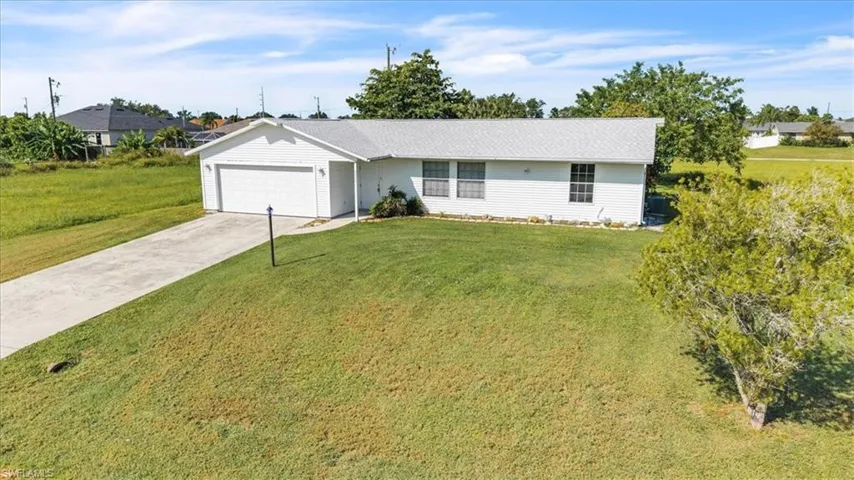 Single story home with concrete driveway, an attached garage, and a front yard